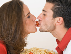 Et par kysser hinanden med en cherrytomat mellem sine læber